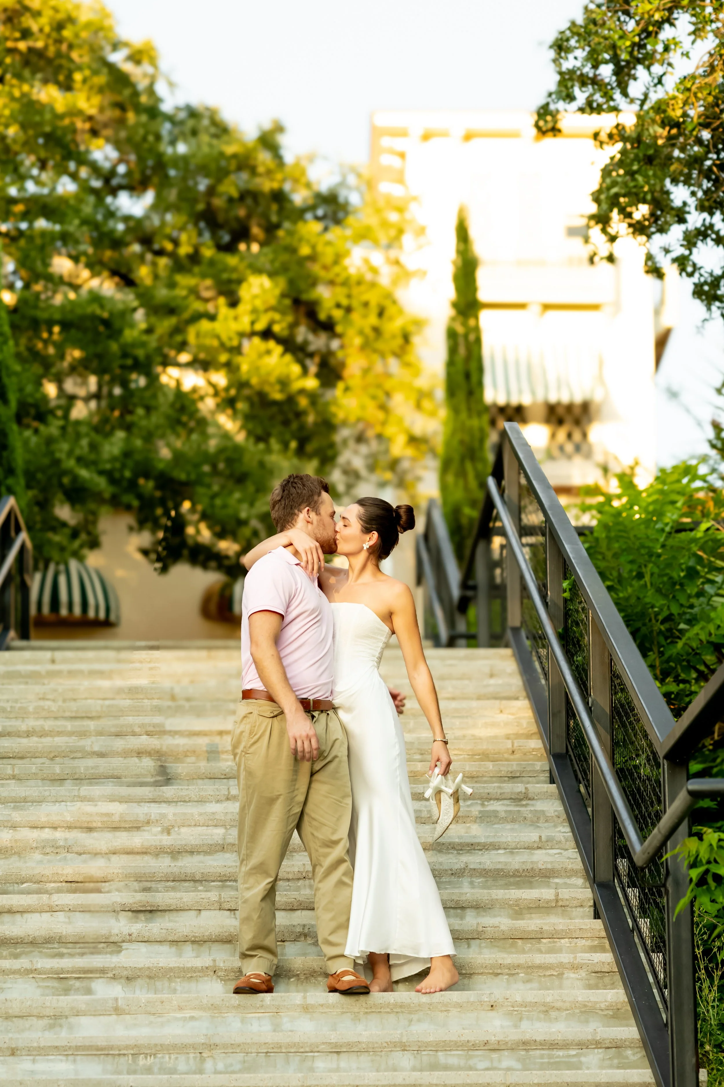 A couple sharing a kiss on outdoor steps in warm sunlight